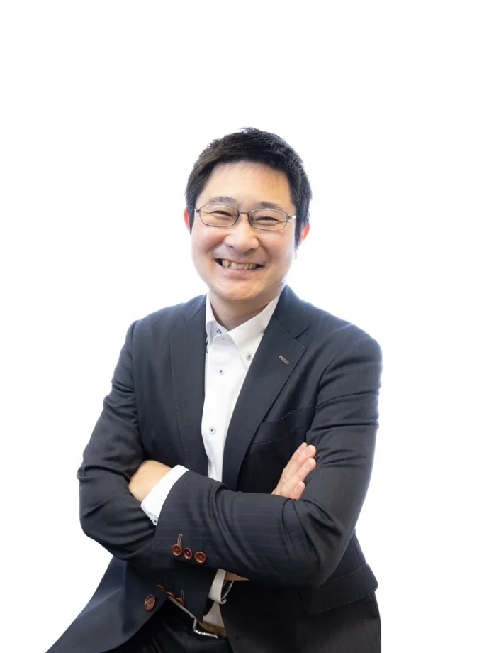 腕を組んで微笑む代表取締役社長 小柳 博之